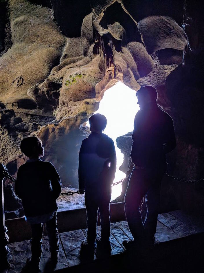 Three people in sea cave. 