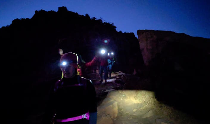 Hikers in the dark with headlamps.