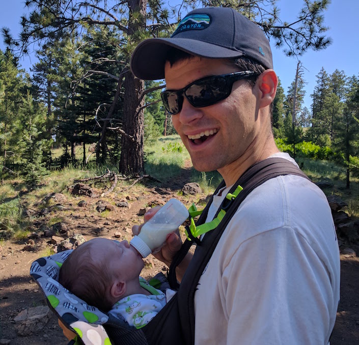 my husband with a newborn in the woods