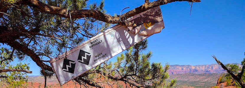 "most difficult" mountain biking sign hanging on a tree