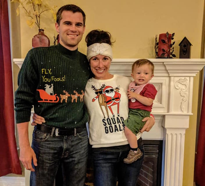 Me and my husband in Christmas sweaters with the baby in red and green