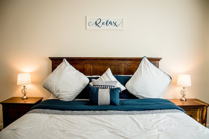 Bedroom w/ "Relax" sign over bed. 