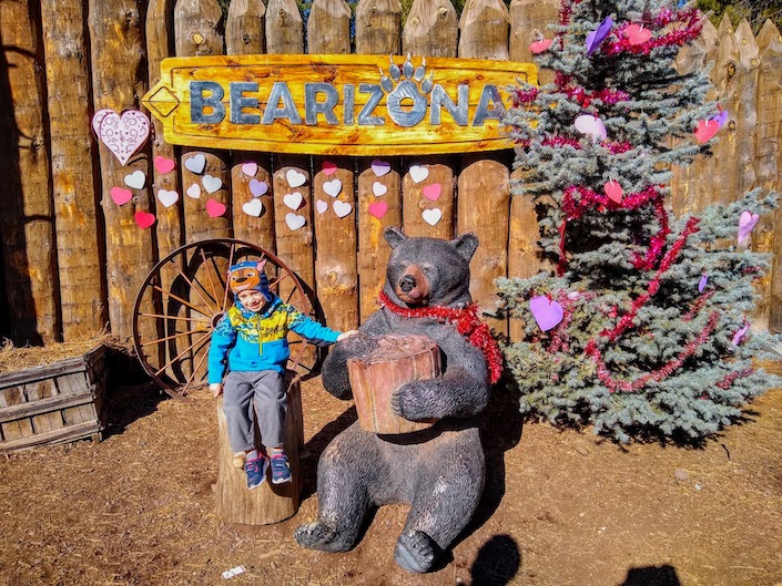 Kid at Bearizona w/ wooden bear and Valentine's day decor. 
